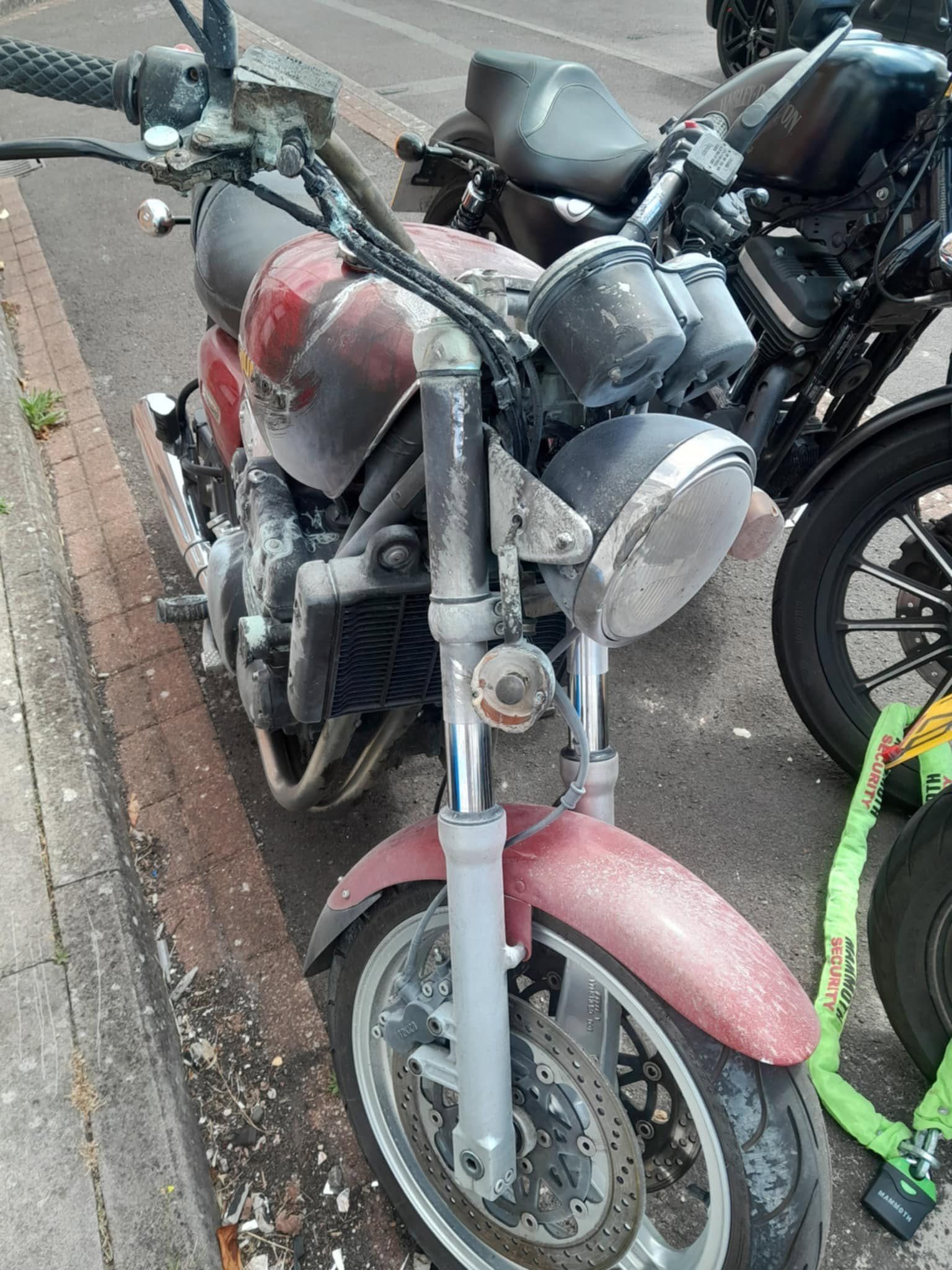 Fire damaged red Triumph motorcycle before repair