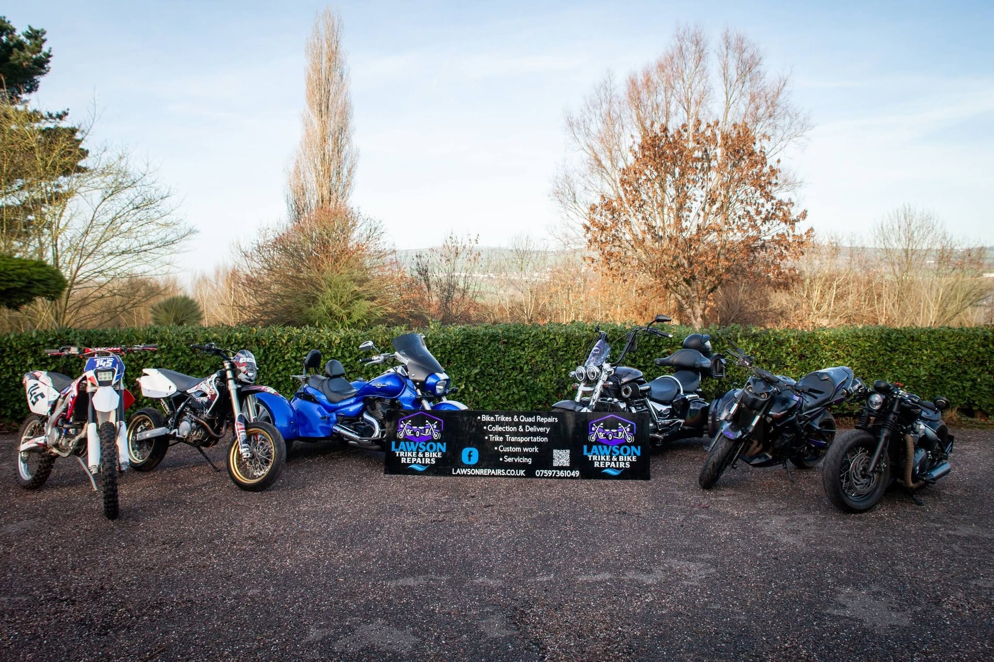 Bikes and trikes lined up with a Lawson Repairs banner