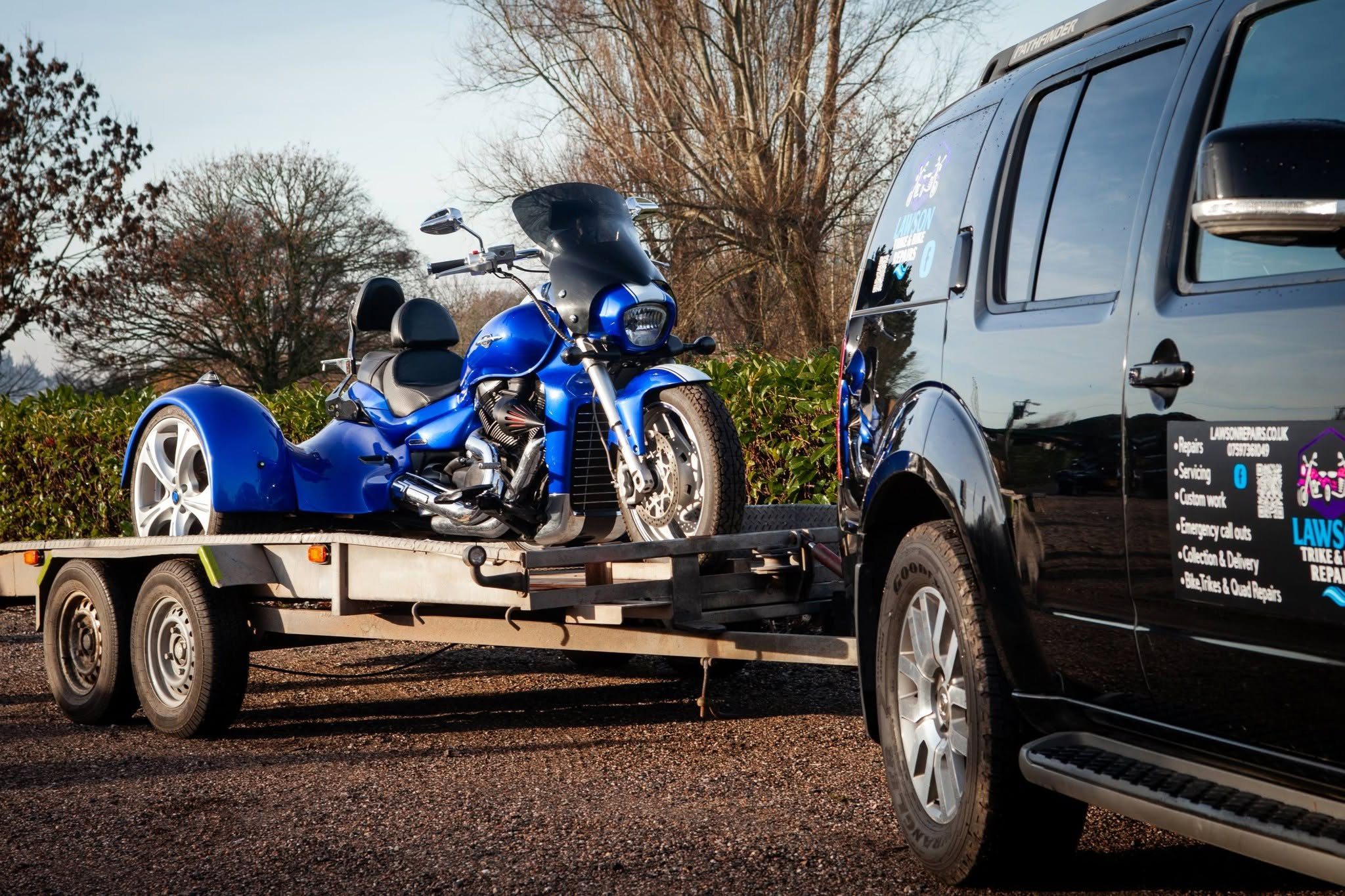 Blue trike secured on a trailer next to the Lawson Repairs van
